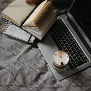 A cozy home office setup featuring a laptop, open notebooks, and a cup of coffee, promoting productivity and comfort.
