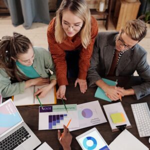 Top view of a diverse group discussing business reports and charts around a desk.